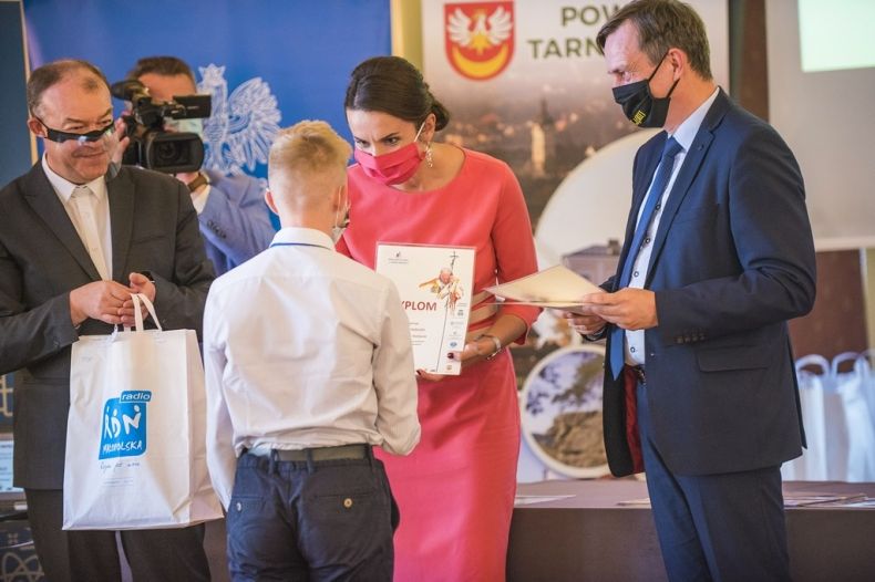 ludzie w maseczkach stoją podczas rozdania nagród