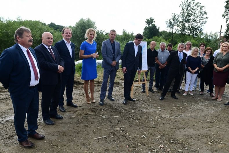 Duża grupa osób stojących obok siebie. Spotkanie odbywa się w pobliżu brzegu rzeki