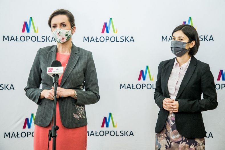Marta Malec-Lech z zarządu województwa oraz zastępca dyrektora Agata suszczyńska stoją na tle ścianki z napisami Małopolska.