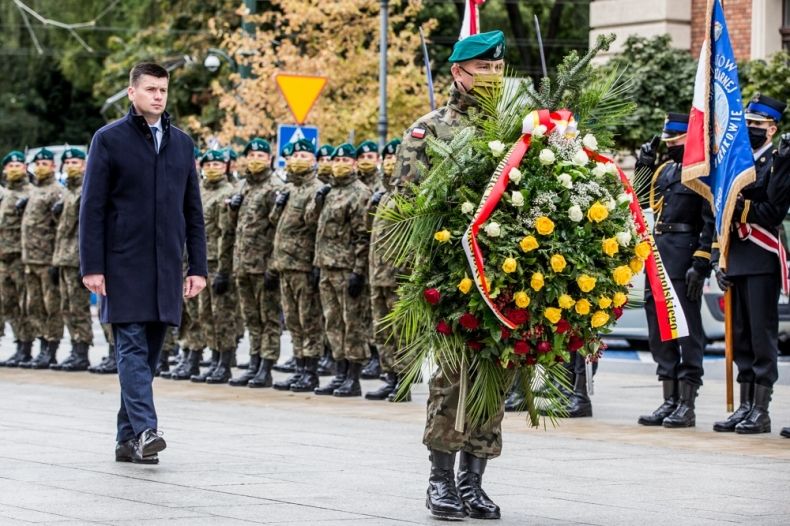 Marszałek lukasz Smółka idzie za żołnierzem z wieńcem. Na placu w tle żołnierze