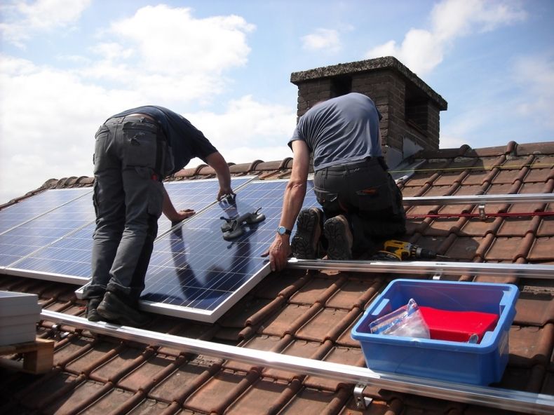 dwaj mężczyźni pracują na dachu, montując panele fotowoltaiczne