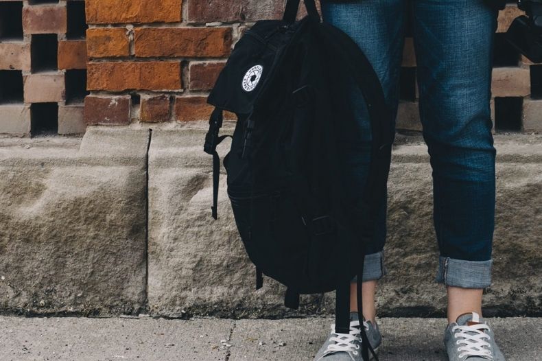 Zdjęcie przedstawia ucznia trzymającego plecak szkolny