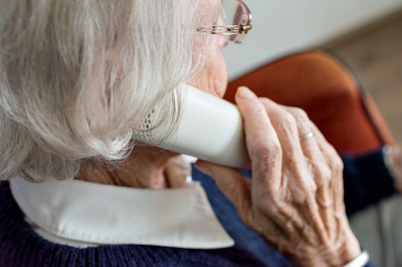 Starsza kobieta trzymająca słuchawkę telefonu