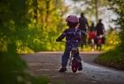 Zdjęcie przedstawia dziecko jadące na rowerku, w oddali dorośli rowerzyści