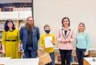 Marta Malec-Lech z zarządu województwa stoi z chłopcem trzymającym dyplom, w towarzystwie innych ludzi.