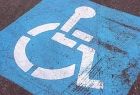 Znak dla osób z niepełnosprawnościami - na niebieskim tle widoczne białe kontury osoby siedzącej na wózku inwalidzkim.