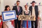 Wicemarszałek Łukasz Smółka stoi z przedstawicielami sołectwa Powroźnik. Ubrani są oni w stroje ludowe.