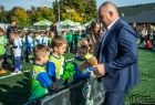 Radny województwa Robert Bylica wręcza puchary dzieciom na boisku.
