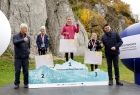 Wicemarszałek Łukasz Smółka razem z dziećmi stojącymi na podium.