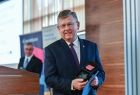 Marszałek Witold Kozłowski trzyma w rękach odznaczenia.