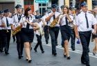 Orkiestra Dęta OSP w Tęgoborzy maszeruje ulicą i gra ubrana w strażackie mundury galowe.