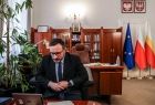 Wicemarszałek Tomasz Urynowicz patrzy w ekran podczas spotkania online, w tle wnętrze gabinetu marszałka