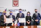 Marszałek Witold Kozłowski i wicemarszałek Łukasz Smółka prezentujący aneks dotyczący kontynuacji Małopolskiego Tele-Anioła oraz: radna Marta Mordarska, Dawid Konina – zastępca dyrektora Departamentu Rodziny