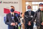 marszałek Witold Kozłowski stoi przed mikrofonem, obok dwóch mężczyzn