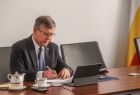 Marszałek podczas posiedzenia zarządu. Siedzi za stołem. Na stole filiżanka, dokumenty, urządzenia biurowe.
