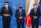 wojewoda Łukasz Kmita, marszałek Witold Kozłowski oraz wójt Stanisław Gorajczyk na tle niebieskiej ścianki i flag