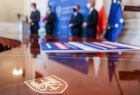 burmistrz Zakliczyna Dawid Chrobak, wojewoda Łukasz Kmita, marszałek Witold Kozłowski oraz wójt Stanisław Gorajczyk na tle niebieskiej ścianki i flag - rozmyci; widok na stół