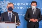 marszałek Witold Kozłowski - przemawia do mikrofonu, wojewoda Łukasz Kmita, stoją na tle niebieskiej ścianki