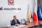 Marszałek Małopolski podczas posiedzenia zarządu, w tle napis MAŁOPOLSKA i flagi: krajowa, wojewódzka i UE
