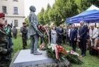 Widok na pomnik oraz gości uroczystości stojących w rzędzie