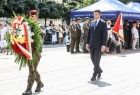 Żołnierz niosący wieniec, za nim wicemarszałek Łukasz Smółka