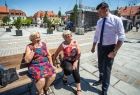 Wicemarszałek Łukasz Smółka rozmawia ze starszymi kobietami siedzącymi na ławce w rynku.