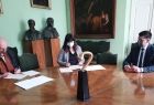 Wicemarszałek Łukasz Smółka siedzi przy stole wraz z sygnatariuszami umowy. Kobieta i mężczyzna podpisują umowę.