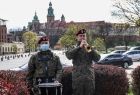 Żołnierze przy Pomniku Polski Walczącej, jeden z nich gra na trąbce. W tle widoczny Wawel.