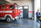 Wicemarszałek Łukasz Smółka wizytuje nową remizę strażacką. W garażu stoi wóz strażacki.
