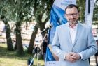 Wicemarszałek Tomasz Urynowicz stoi przed mikrofonem. Z tle baner z napisem Fundusze Europejskie. 