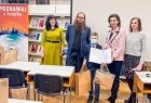 Marta Malec-Lech z zarządu województwa z uczestnikiem konkursu. Obok stoją inni ludzie, z tyłu widoczne kolorowe banery.
