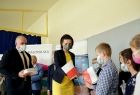 Marta Malec-Lech z zarządu województwa przekazuje flagi dzieciom.