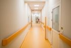 Wyremontowany szpitalny korytarz, charakterystyczne żółte poręcze na ścianach i podłoga.