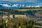 Widok z lotu ptaka na zamek, w tle pola, w oddali widoczny zarys gór