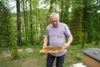 Pszczelarz pokazuje pszczoły, w tle zieleń.
