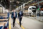 Wicemarszałek Łukasz Smółka w towarzystwie mężczyzny zwiedza zakład. Z tyłu widoczna biała ciężarówka.