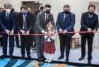 Wicemarszałek Łukasz Smółka przecina wstęgę w towarzystwie innych osób.