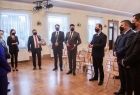 Wicemarszałek Łukasz Smółka przemawia na stojąco w towarzystwie innych osób.