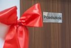 Nowe drzwi przedszkola z przymocowaną czerwoną kokardą.