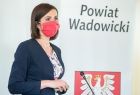 Marta Malec-Lech z zarządu województwa stoi i mówi do mikrofonu. W tle widoczny napis Powiat Wadowicki.