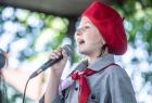 Dziewczynka z mikrofonem w ręce śpiewająca w trakcie konkursu piosenki patriotycznej