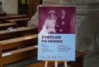 Plakat ze zdjeciem i napisem "Zawołani po imieniu" postawiony w kościele przed ławkami.