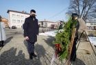 Wicemarszałek Łukasz Smółka stoi wyprostowany przed pomnikiem pamięci