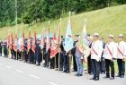 Uczestnicy uroczystości stoją w rzędzie wzdłuż ulicy