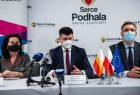 Poseł Anna Paluch, wicemarszałek Łukasz Smółka i wój Rafał Szkaradziński siedzą przy stole konferencyjnym, na tle bannerów