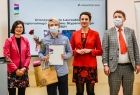 Marta Malec-Lech z zarządu województwa stoi z uczniem który otrzymał stypendium. Obok na scenie stoją inni ludzie.