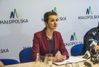 Marta Malec-Lech z zarządu województwa siedzi za biurkiem obok policjanta i mówi do mikrofonu. W tle widoczny napis Małopolska.