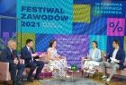 Dyskusja otwierająca program drugiego dnia festiwalu: pięć osób siedzi na kanapach na tle ekranu interaktywnego z nazwą Festiwalu Zawodów