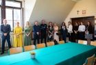 Marta Malec Lech z zarządu województwa stoi wraz z pozostałymi uczestnikami i trzyma podpisaną umowę.
