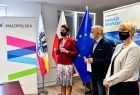 Członkowie zarządu: Marta Malec-Lech i Iwona Gibas podczas wręczania promes. W tle widoczny napis Fundusze Europejskie i Małopolska oraz flagi.